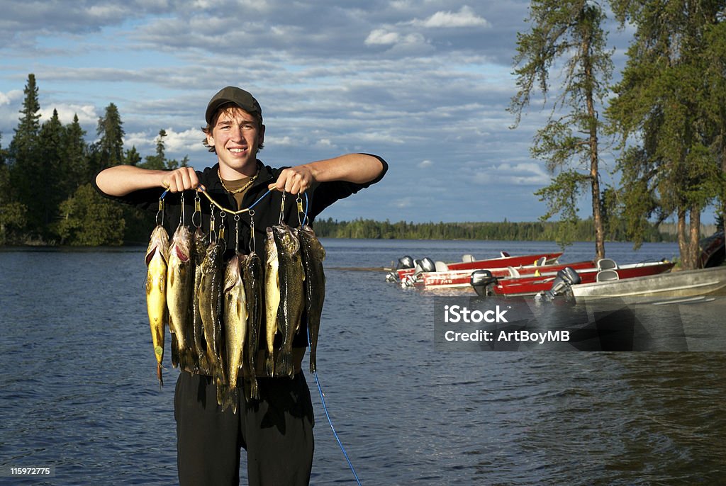 Angler holding a catch of walleye by the lake